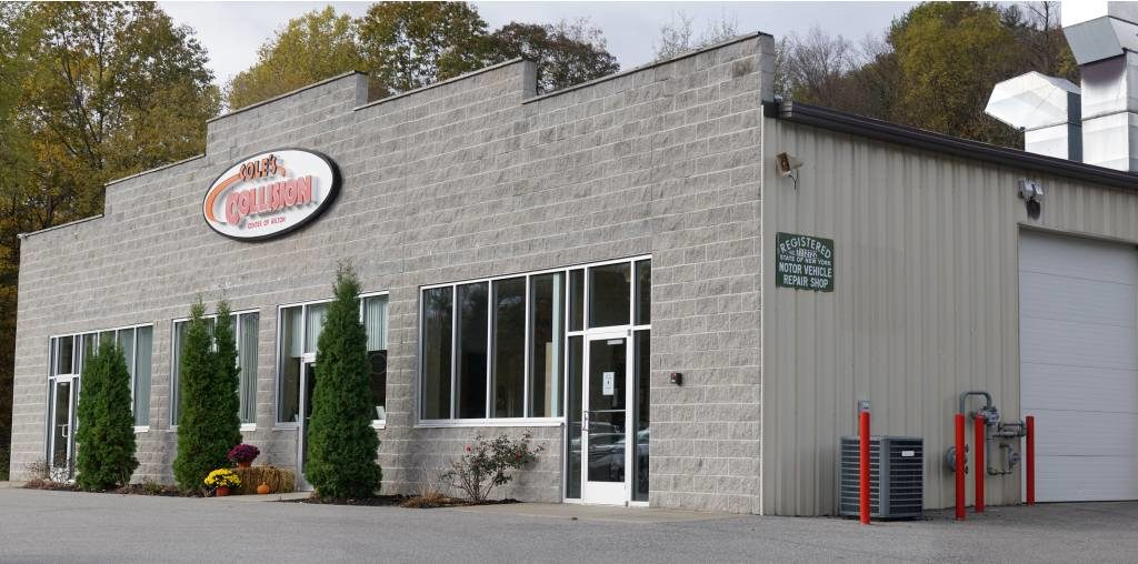 Small brick commercial building with large windows, red sign, and two red gas pumps outside