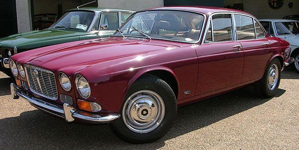 Maroon vintage coupe parked outdoors beside another classic car