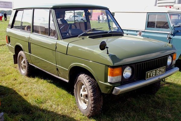Green vintage 4-door SUV parked on grass, shown in front-left view.