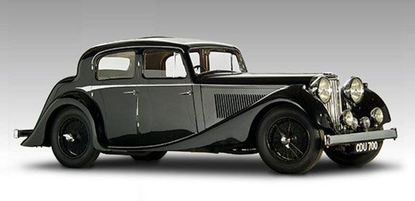 Black vintage coupe with chrome headlights and curved fenders, side view on white background