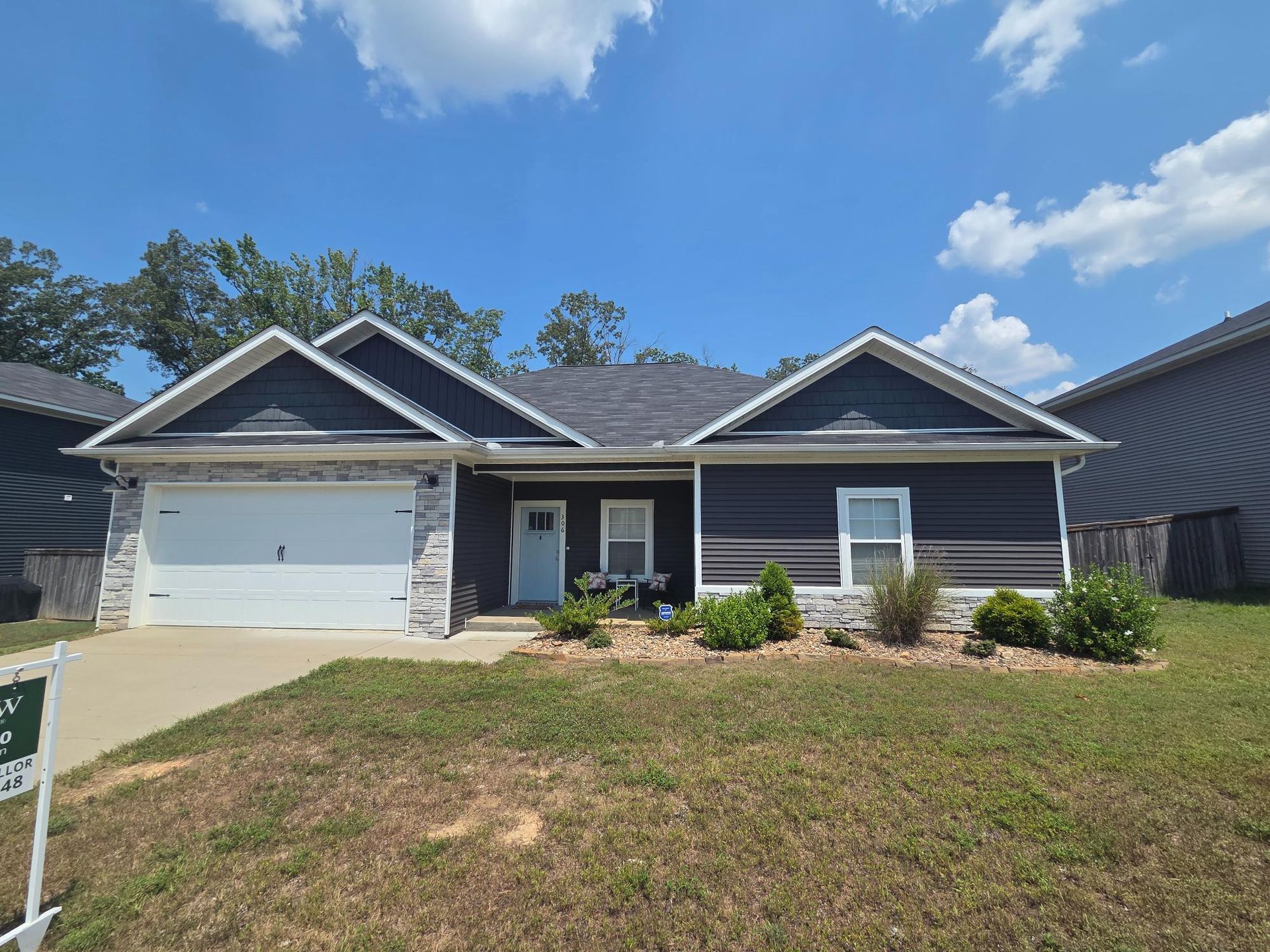 A blue-sided, one-story house with a two-car garage under a bright blue sky.