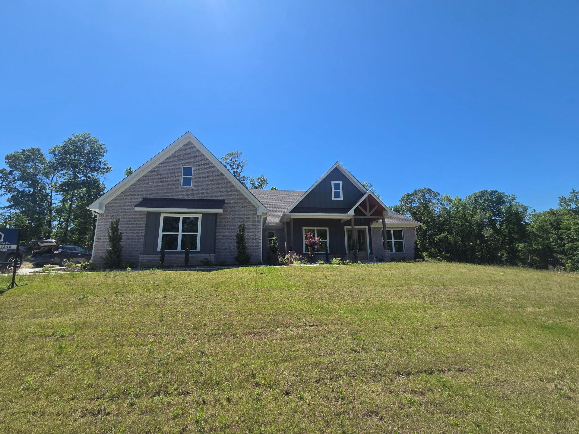 Rural house with stone and wood exterior on a grassy hill under a clear blue sky