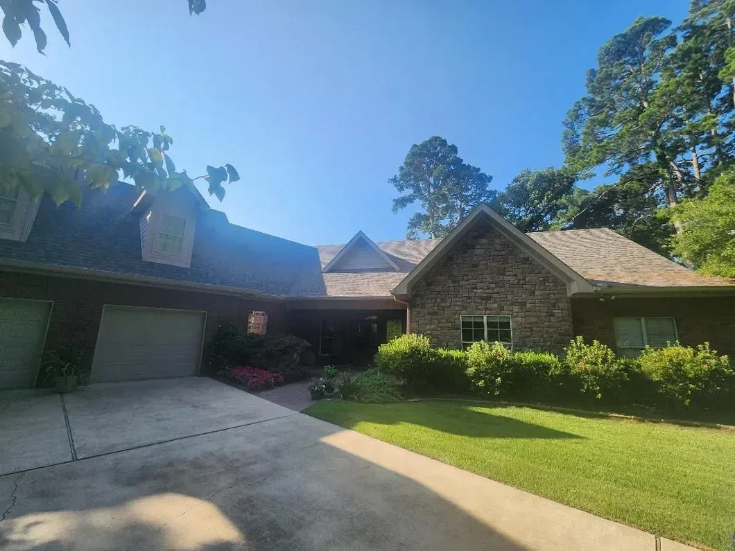A large brick house with a large driveway and a lush green yard.