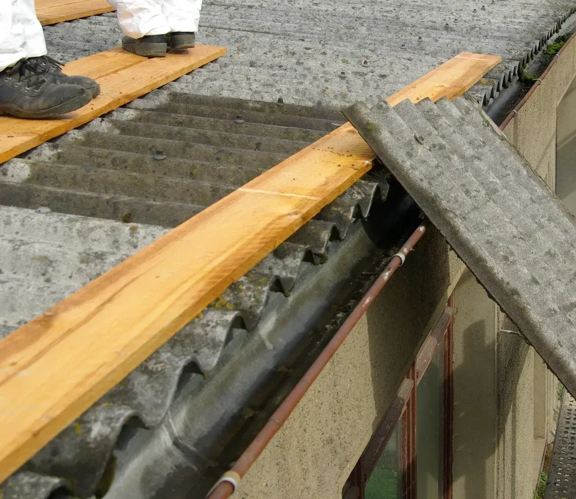 A person is standing on a wooden plank on top of a roof