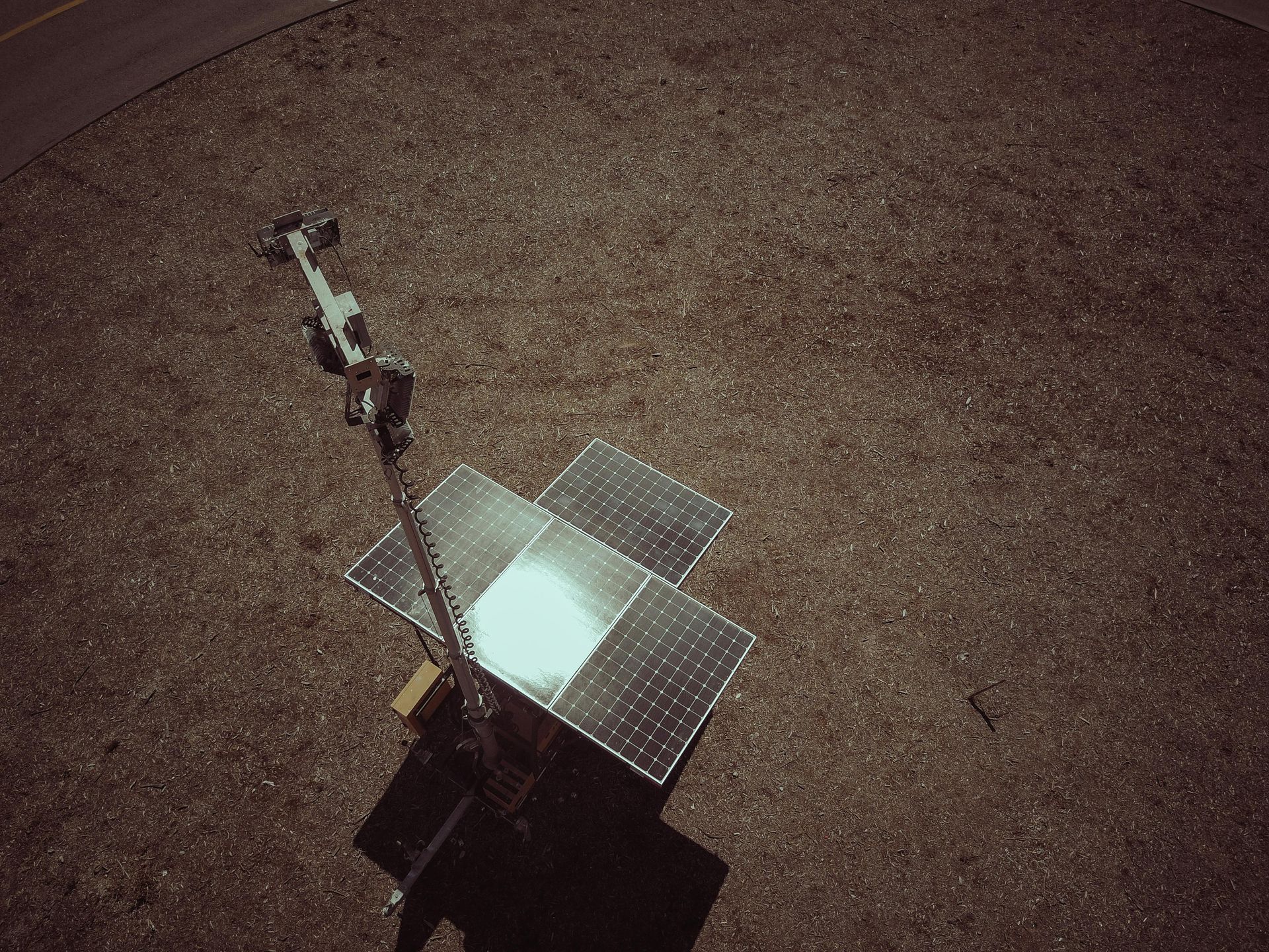 An aerial view of a robot sitting on top of a gravel field.