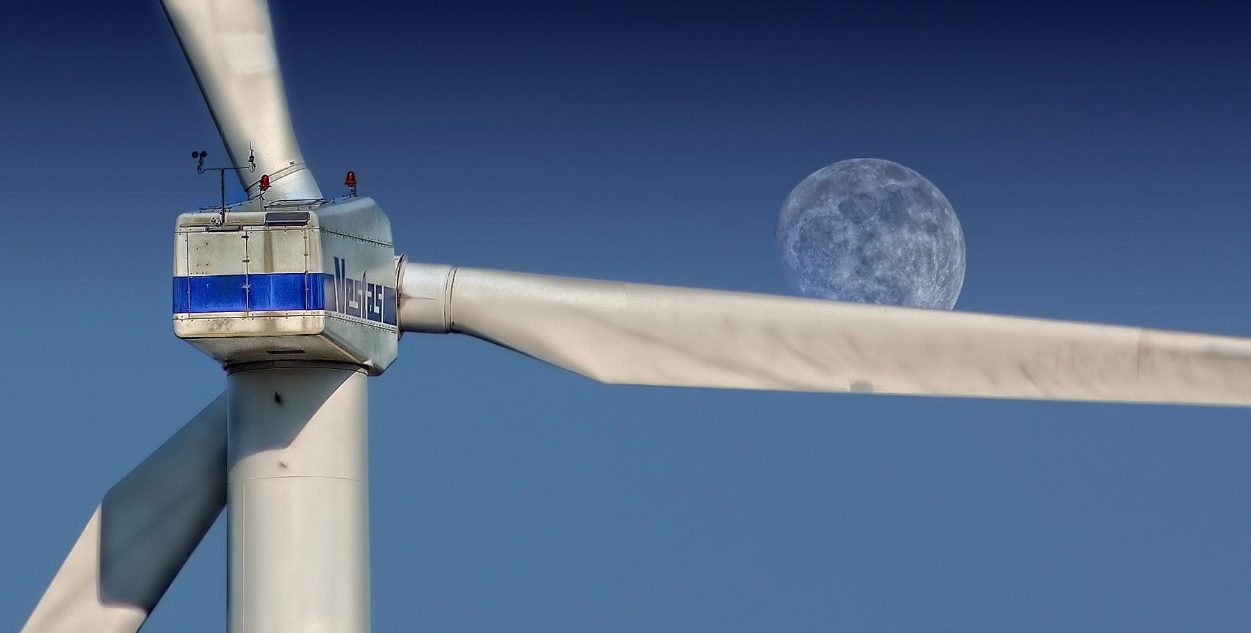 A wind turbine with a full moon in the background
