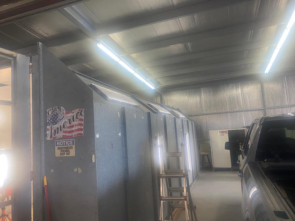 A workshop interior featuring a dark gray wall partition with an American flag decal and a silver truck parked nearby.