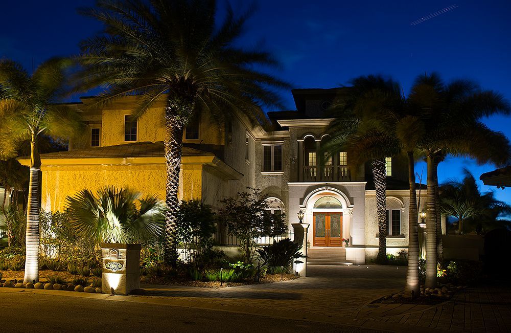 Illuminated luxury house at night with palm trees and a lit front entrance