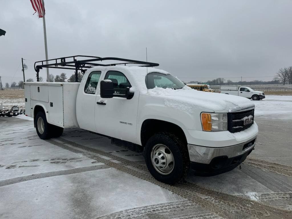 A white truck with a utility bed is parked in a parking lot.