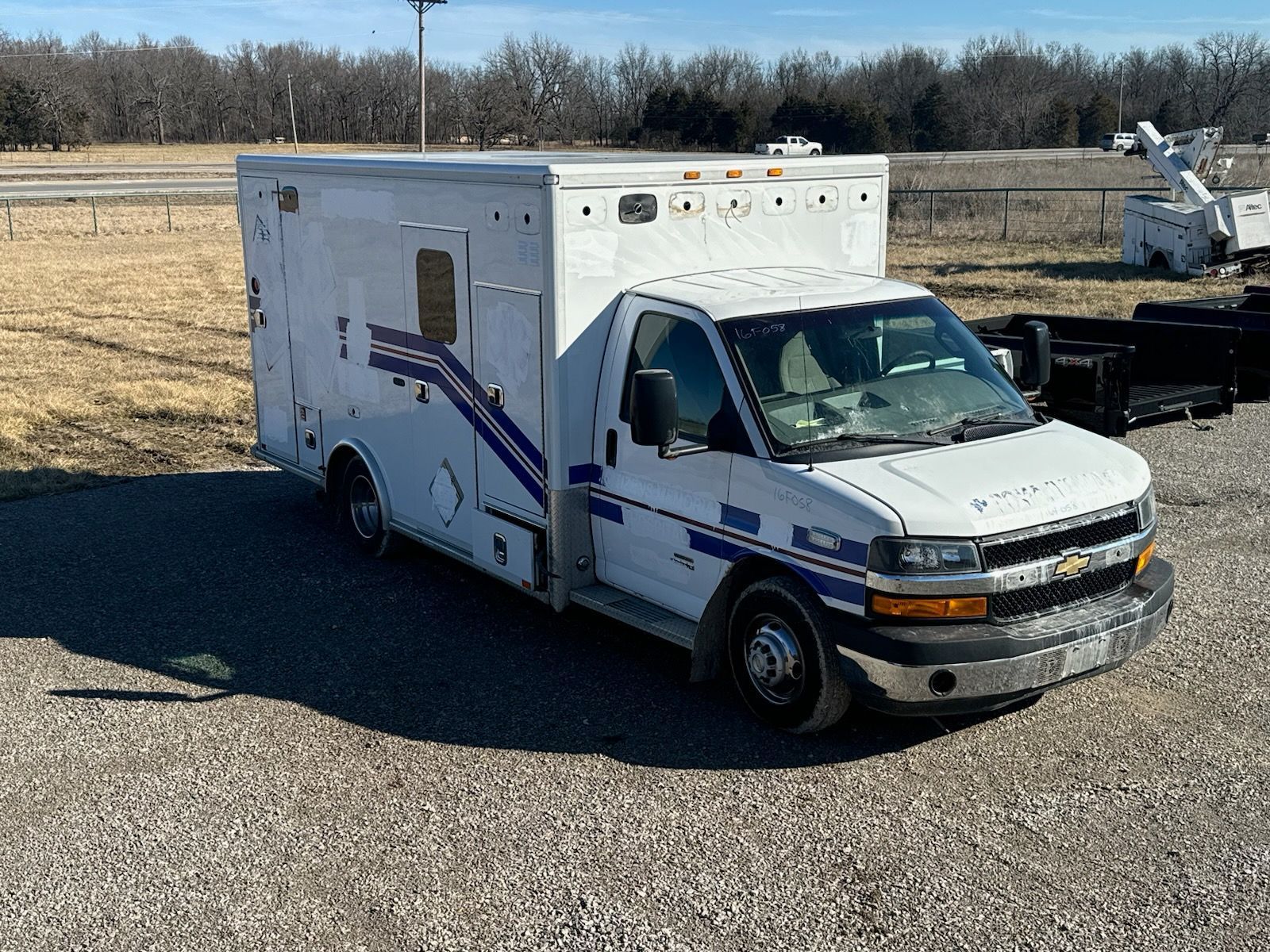 A white ambulance is parked in a gravel lot.