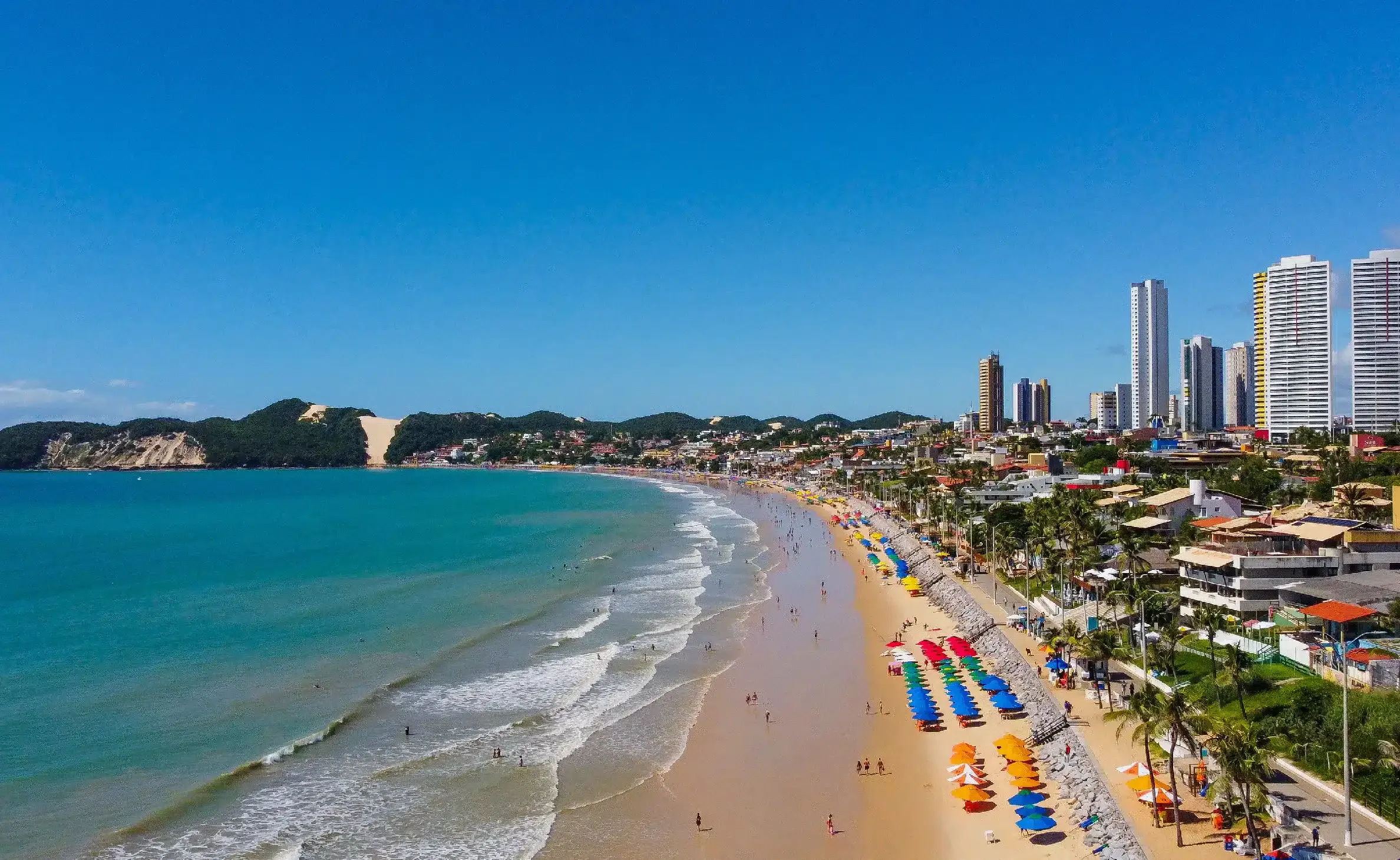 Um grande edifício com muitos carros estacionados na frente. - Pizzato Praia Hotel