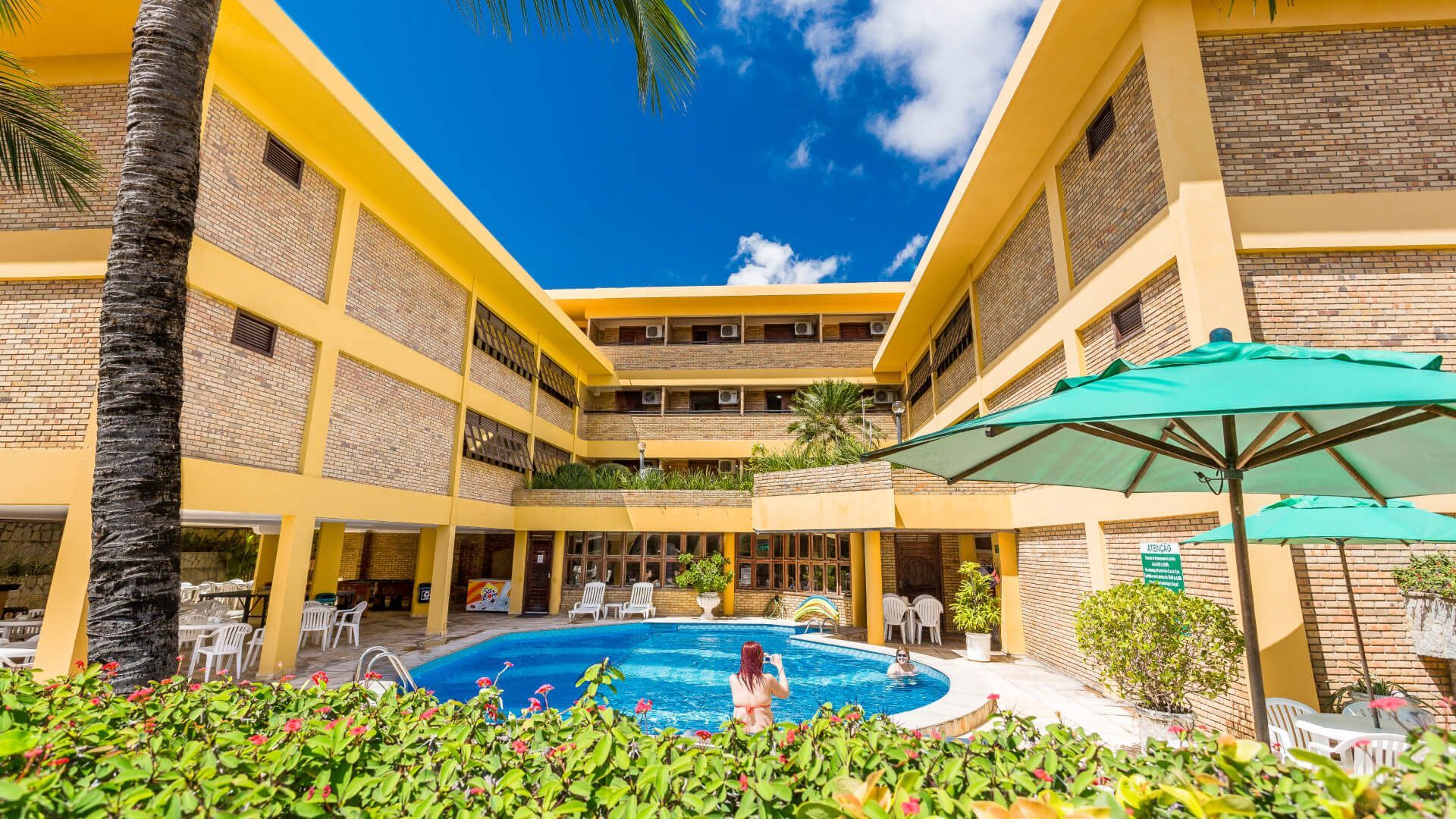 Um grande edifício com uma piscina no meio - Pizzato Praia Hotel