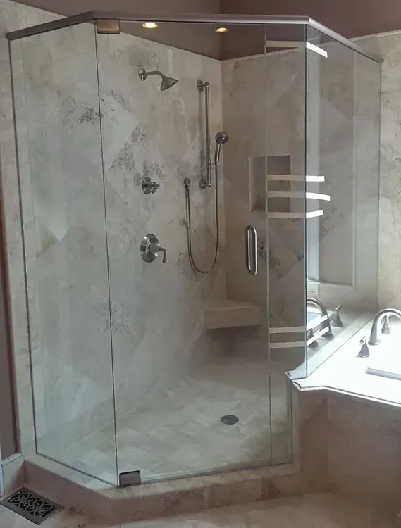 Glass-enclosed beige tiled shower beside a vanity and mirror in a bathroom