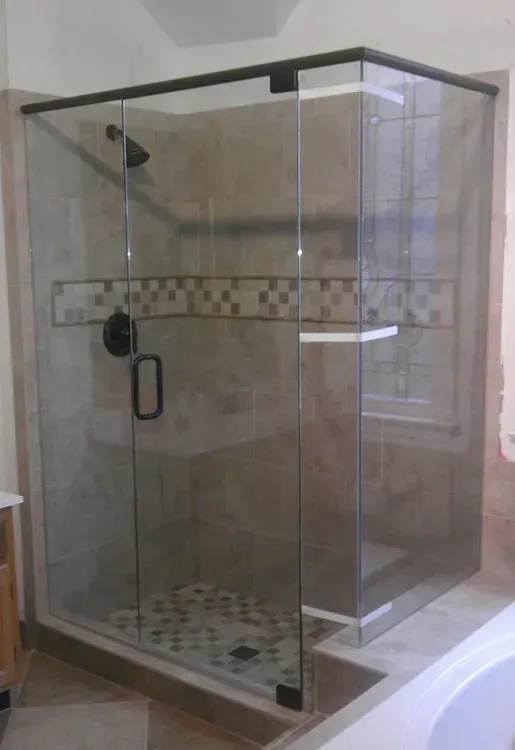 Glass walk-in shower with tiled floor and wall accent in a bathroom.