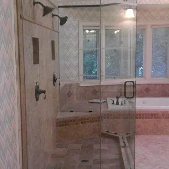 Bathroom with glass shower, tiled walls, and a window above a tub and sink.