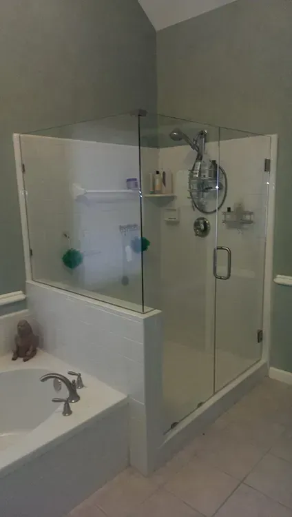 Accessible bathroom with glass shower enclosure and white sink beside it.