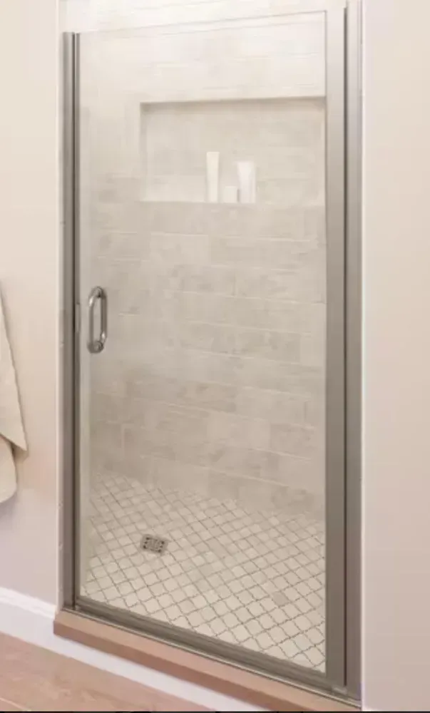 Glass shower door with silver handle, showing a tiled walk-in shower inside.