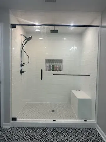 Modern white walk-in shower with handheld showerhead, bench, and textured floor tile