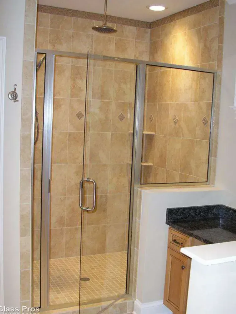 Glass-enclosed walk-in shower with beige tile and a built-in bench beside a bathroom vanity