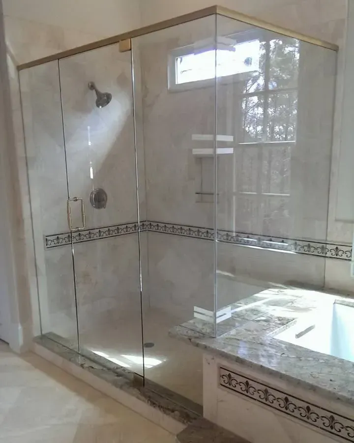 Glass walk-in shower with beige tile and a tiled ledge beside a bathtub opening