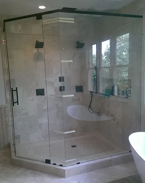 Glass-enclosed corner shower with beige tile, built-in bench, and chrome fixtures