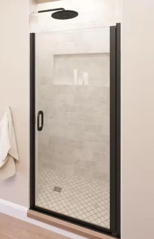 Modern walk-in shower with black-framed glass door in a light tiled bathroom