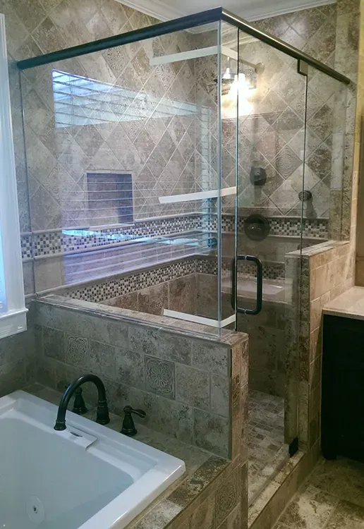 Glass-enclosed walk-in shower beside a white bathtub in a tiled bathroom