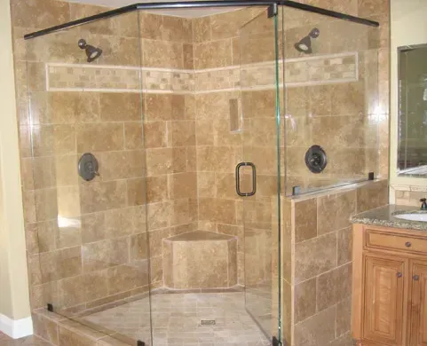 Walk-in glass shower with beige tile walls and corner bench in a bathroom.