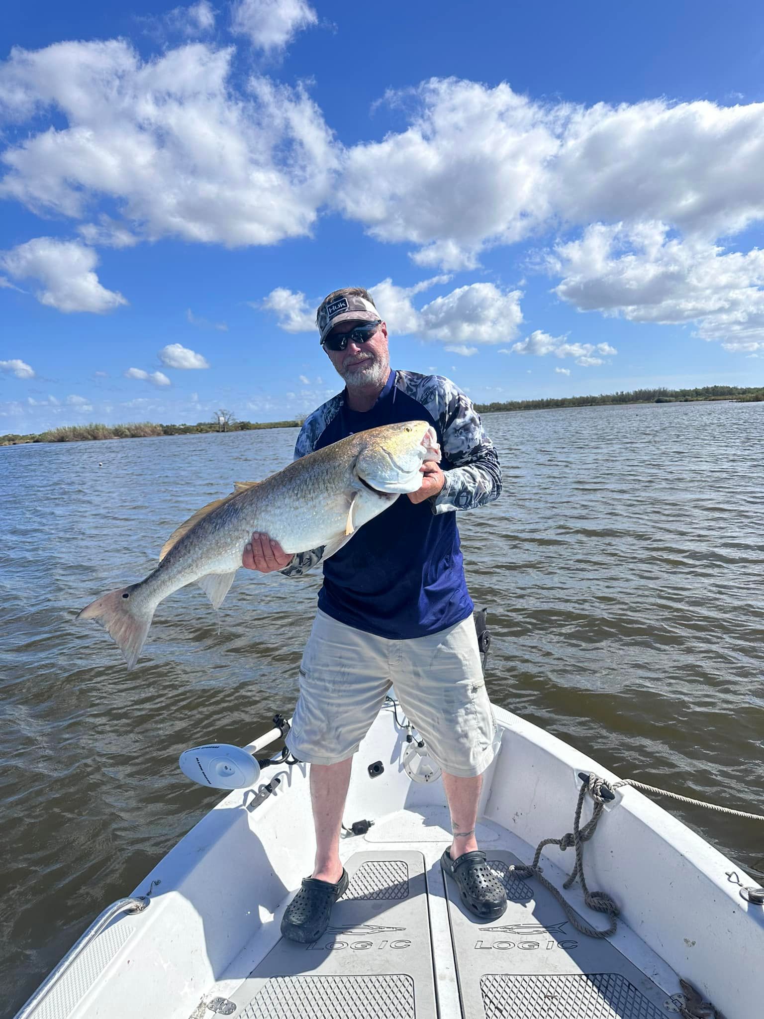 A man is standing on a boat holding a large fish.