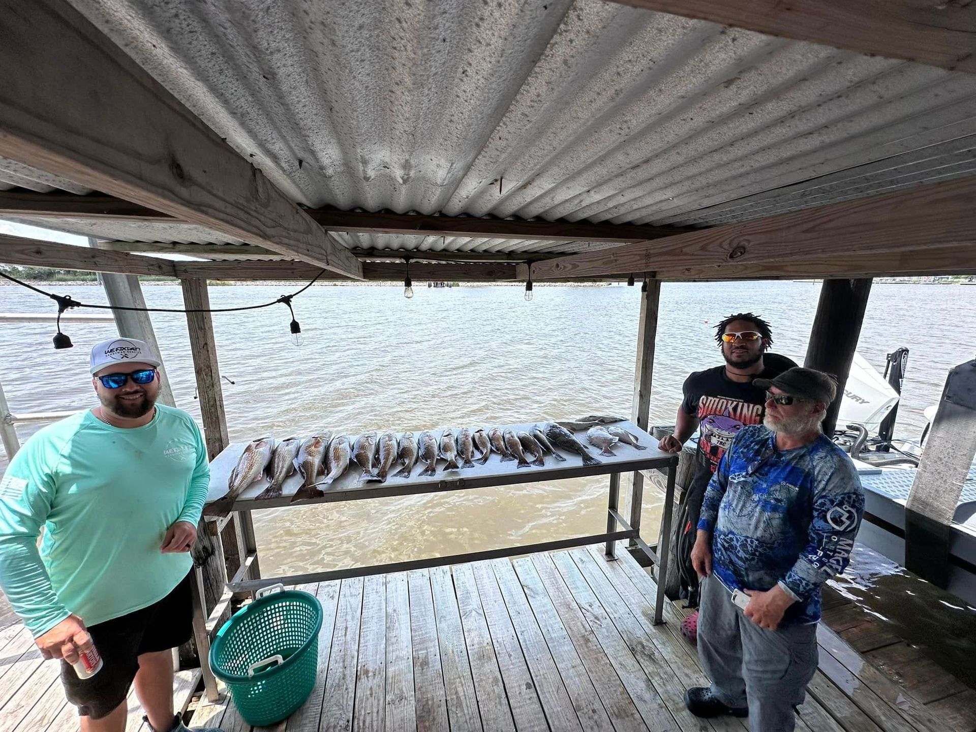 A group of men are standing on a deck next to a table with fish on it.
