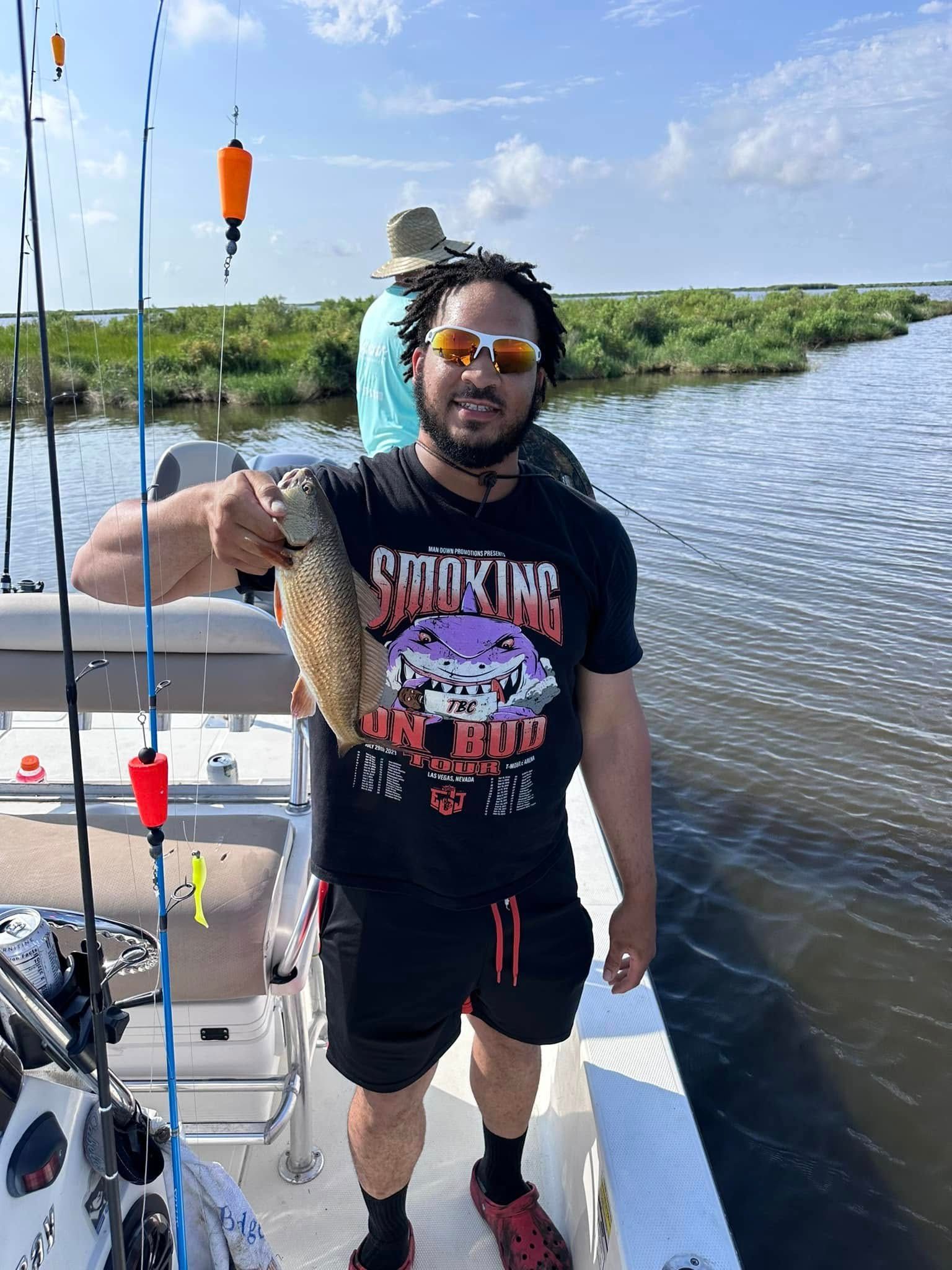 A man is standing on a boat holding a fish.