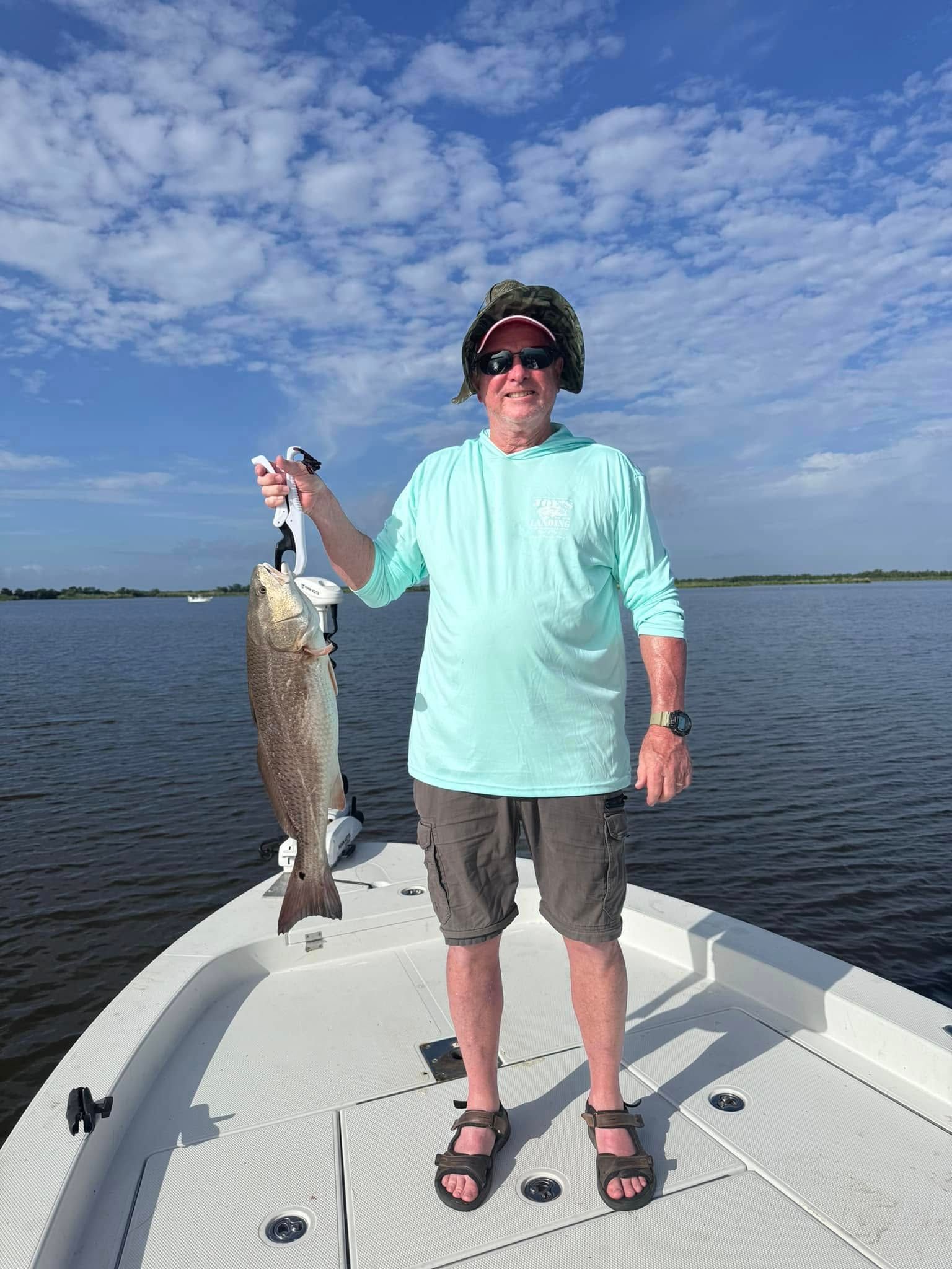 A man is standing on a boat holding a large fish.