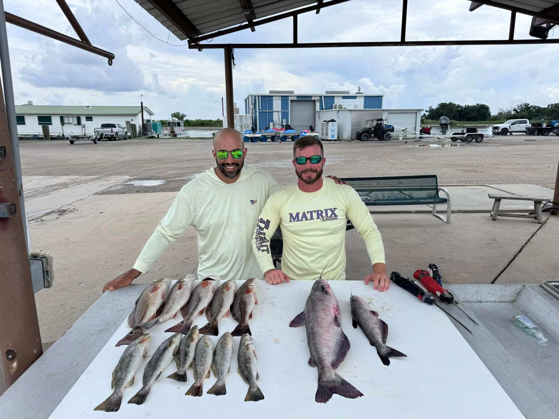 Two men are standing next to a table full of fish.