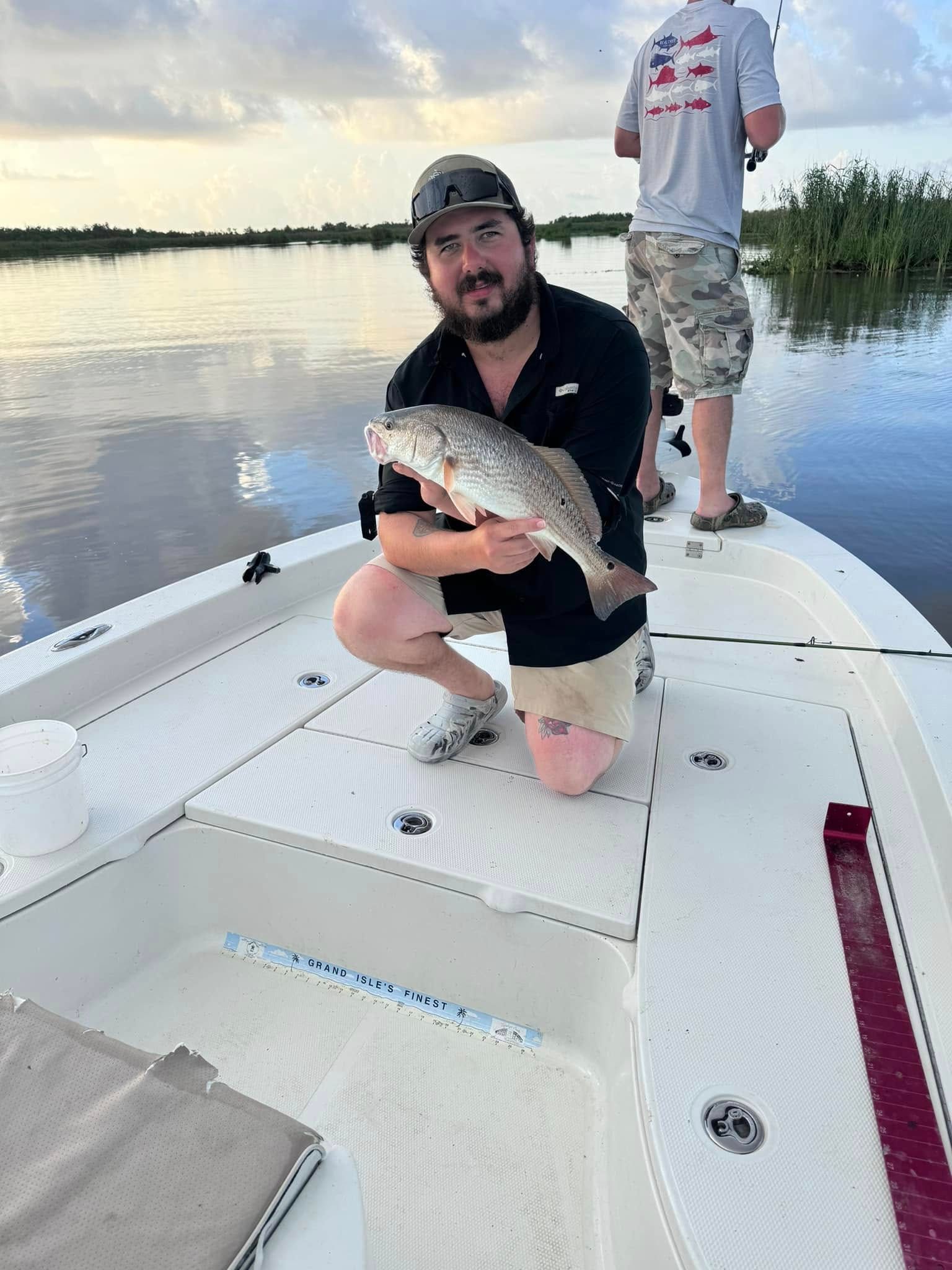 A man is kneeling on a boat holding a fish.