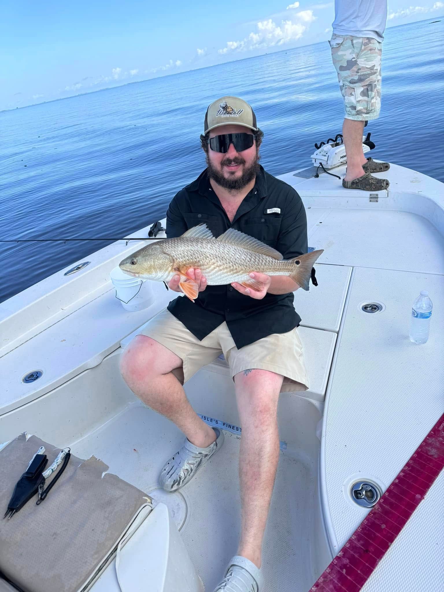 A man is sitting on the back of a boat holding a fish.