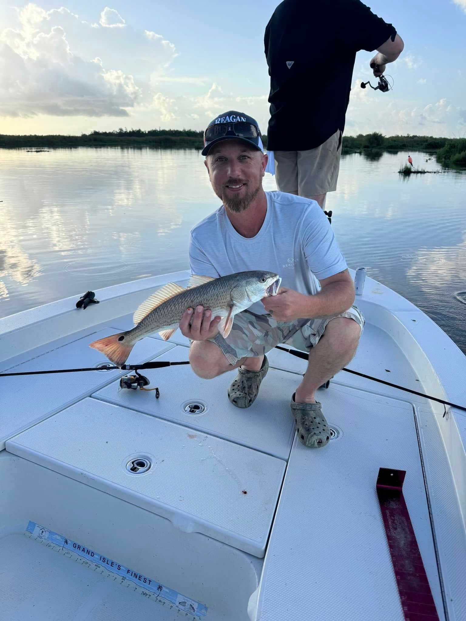 A man is kneeling on a boat holding a large fish.