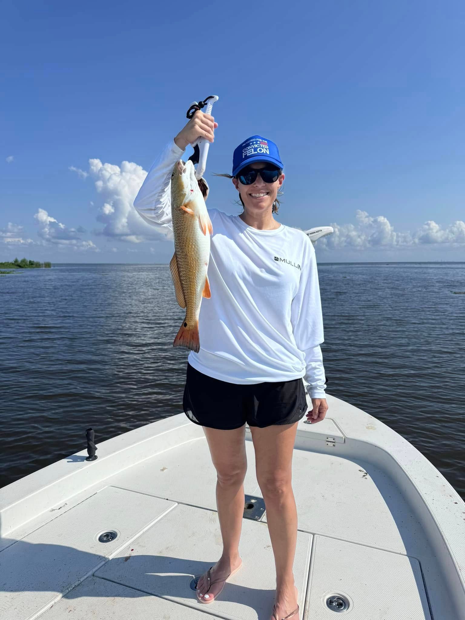 A woman is standing on a boat holding a fish.