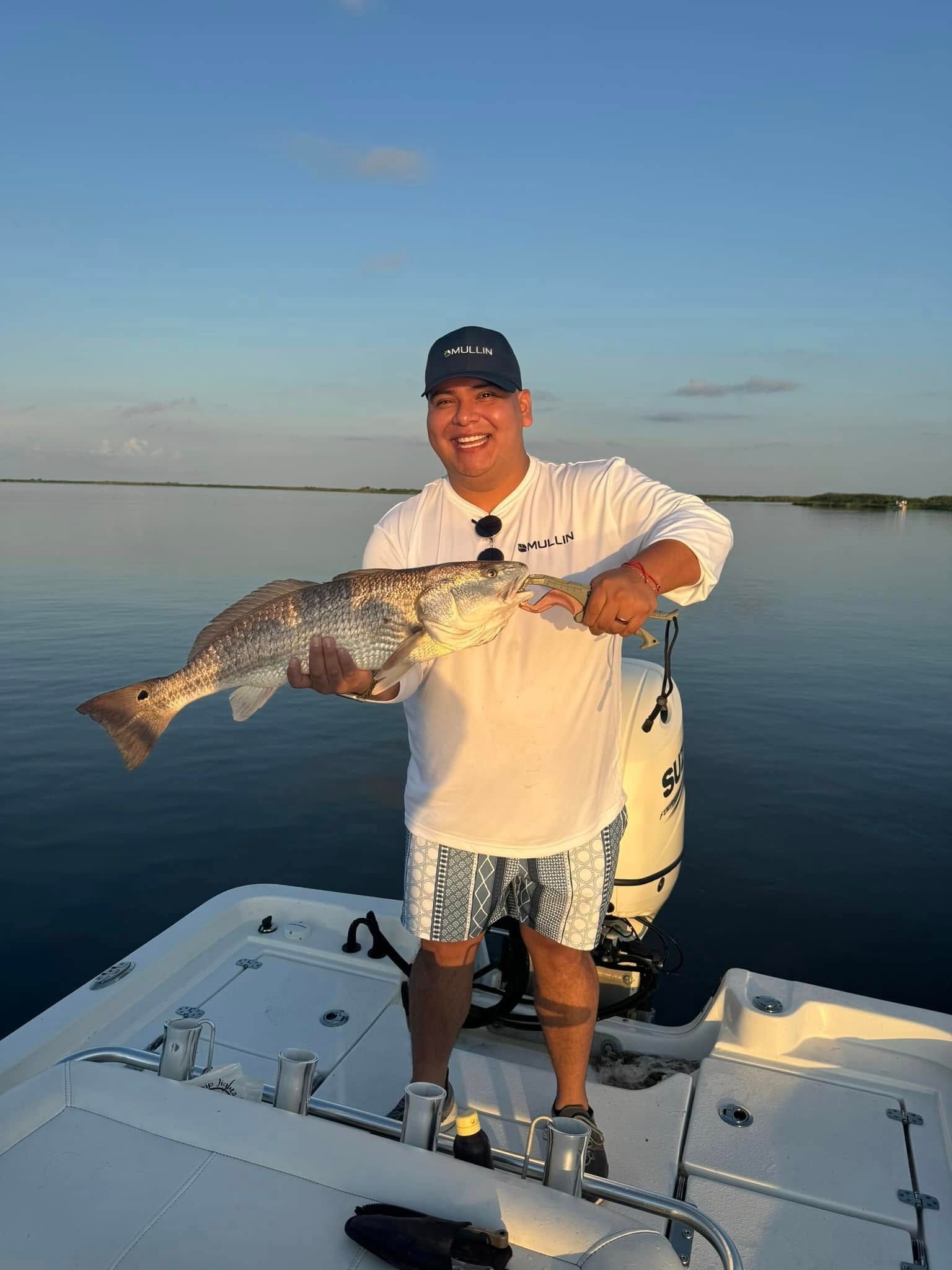 A man is standing on a boat holding a large fish.