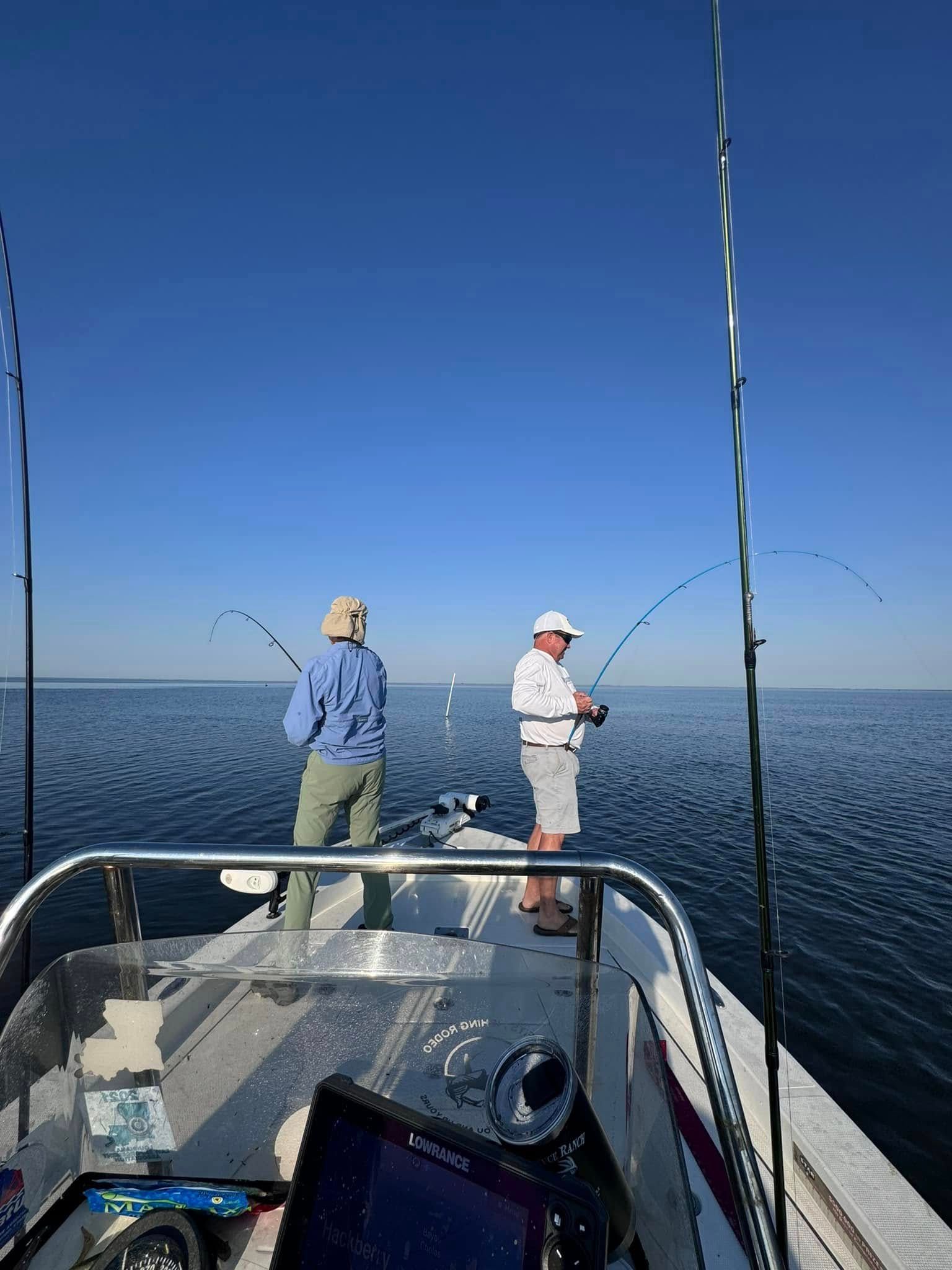 Two people are fishing on a boat in the ocean.