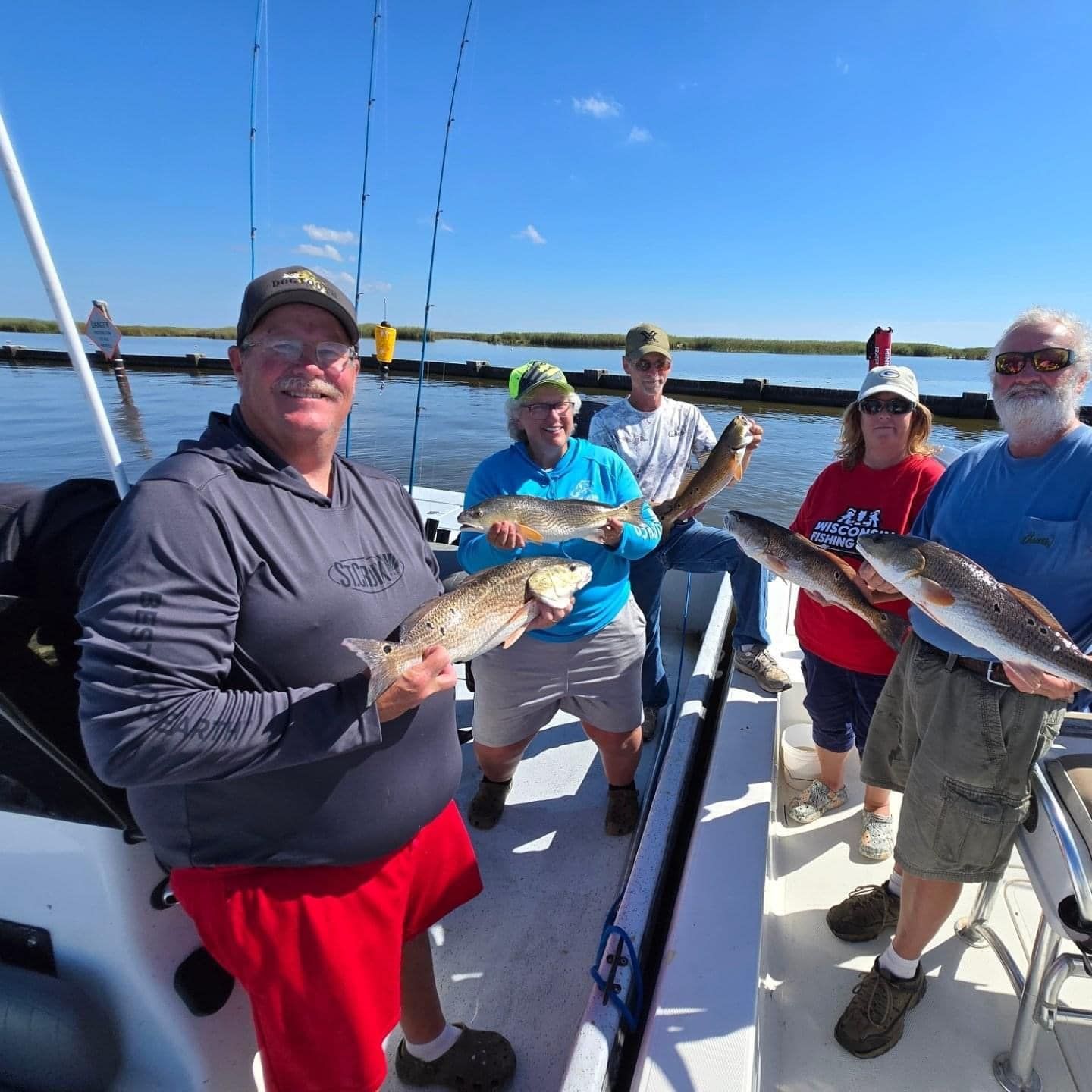 A group of people standing on a boat holding fish