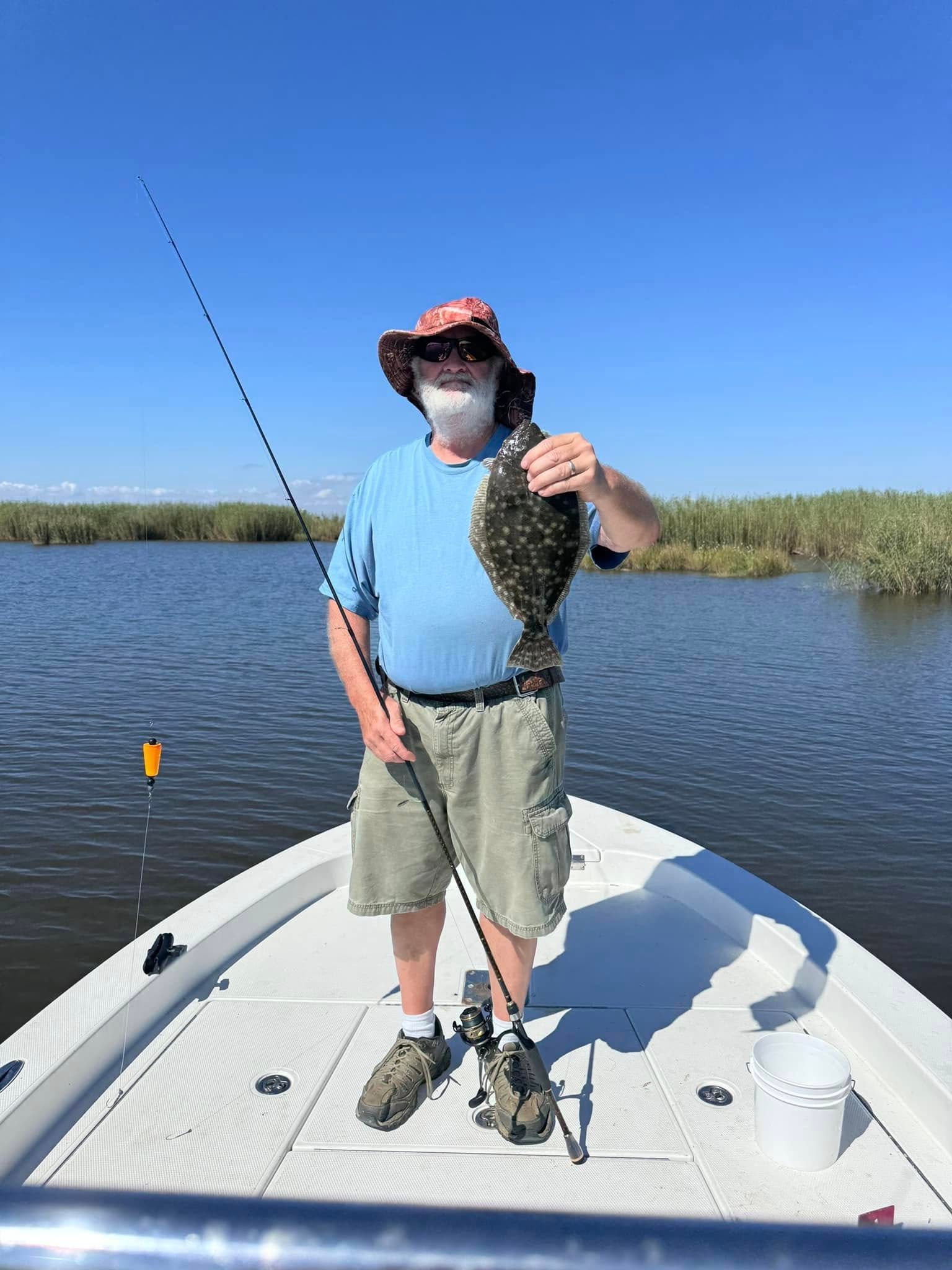 A man is standing on the back of a boat holding a fish.
