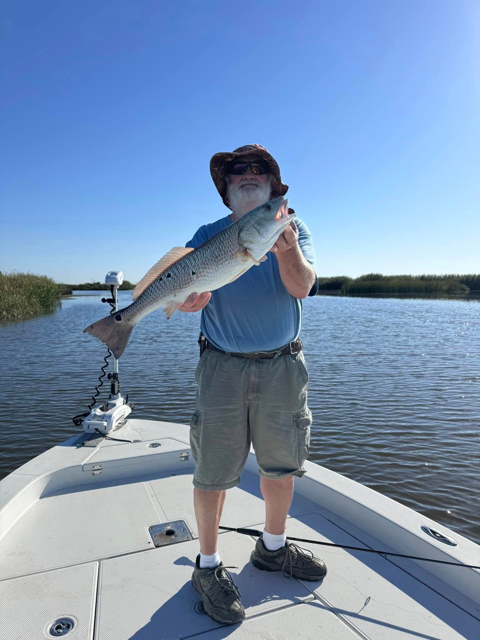 A man is standing on a boat holding a large fish.