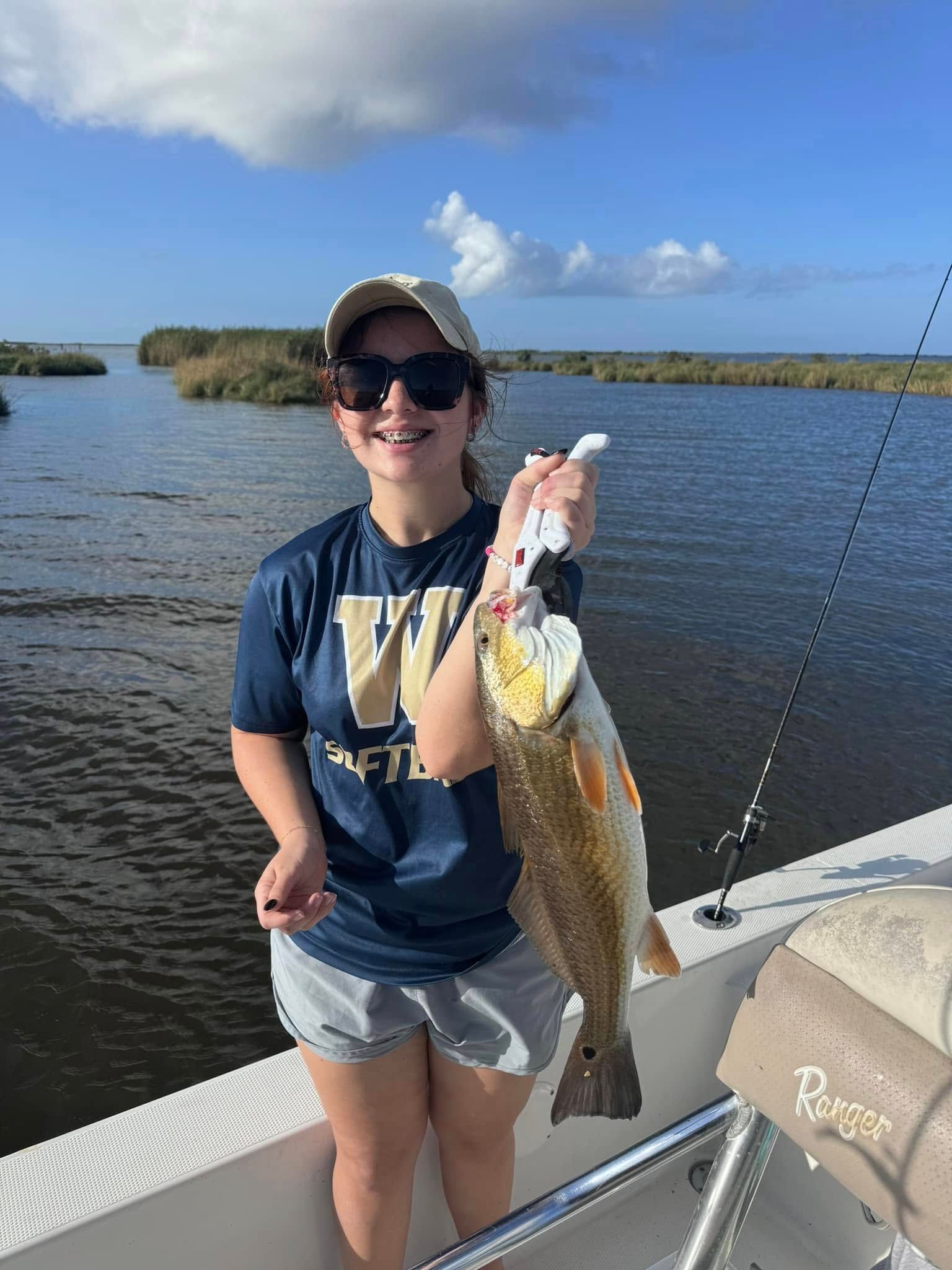 A woman is holding a large fish on a boat.