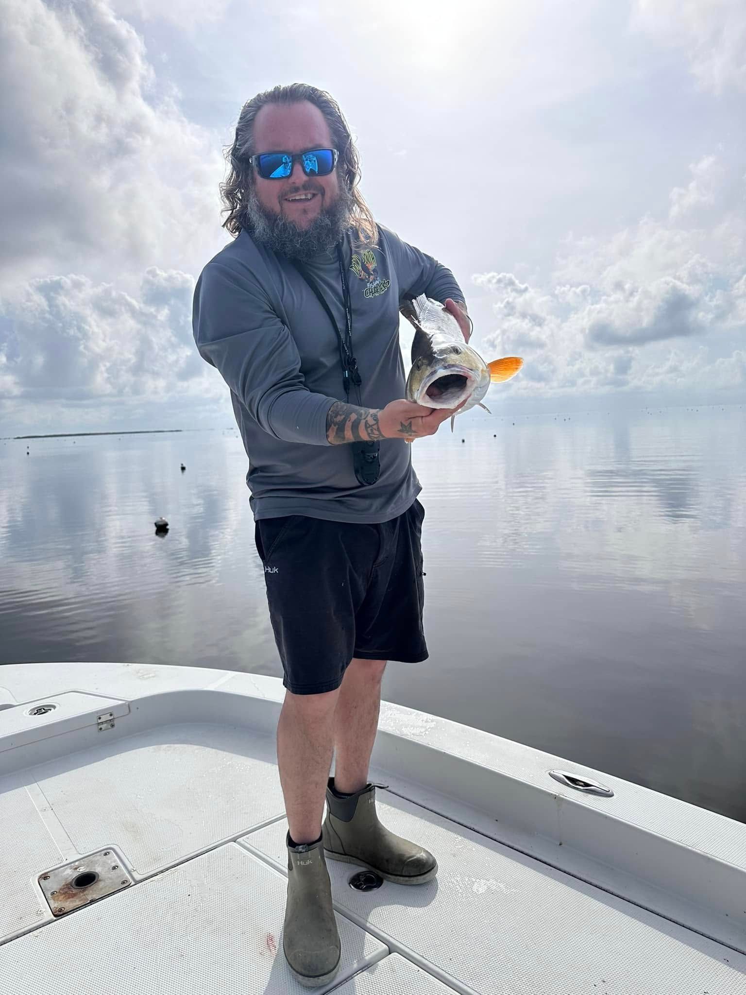 A man is standing on the deck of a boat holding a fish.