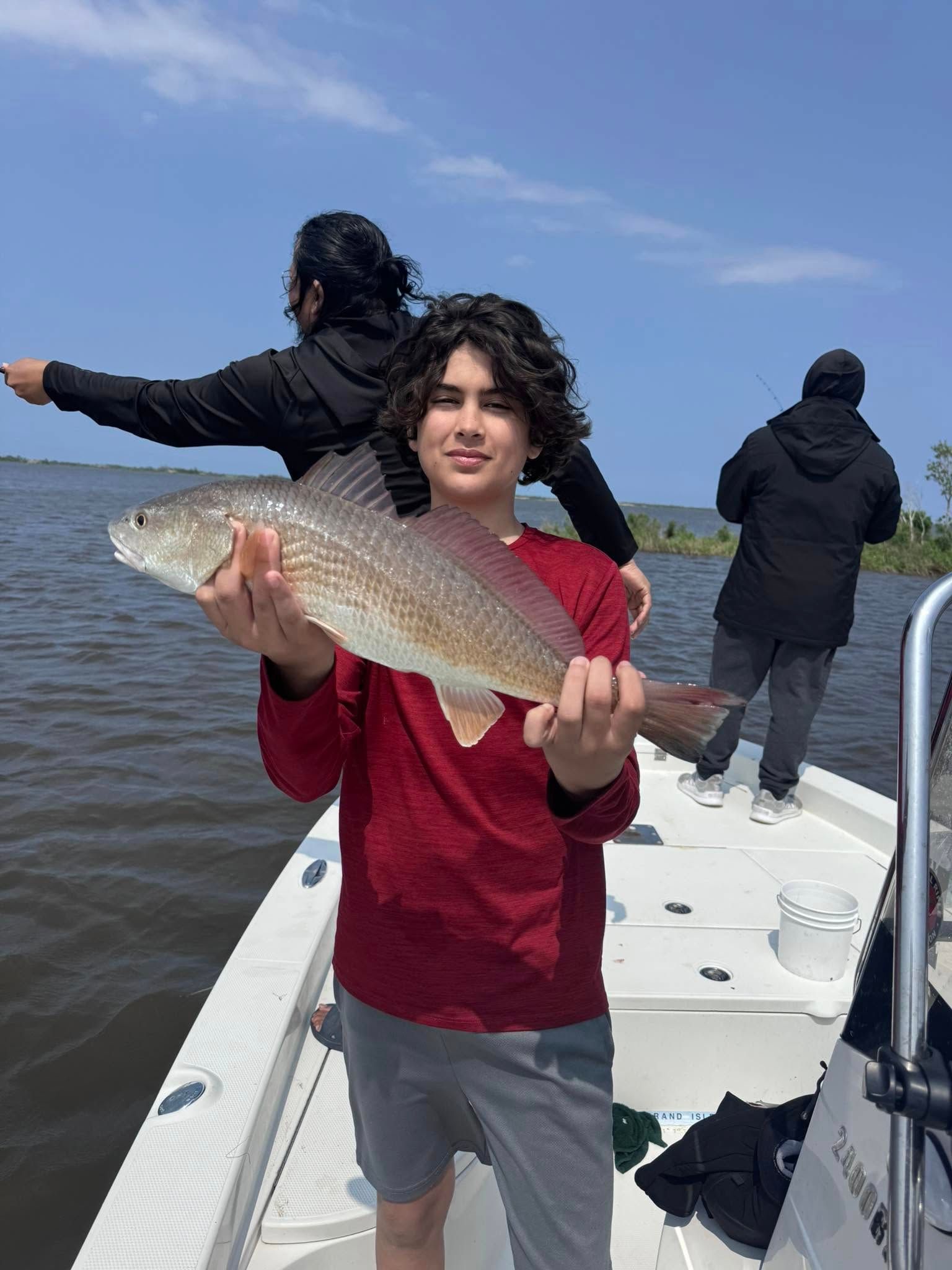 A young boy is holding a large fish on a boat.