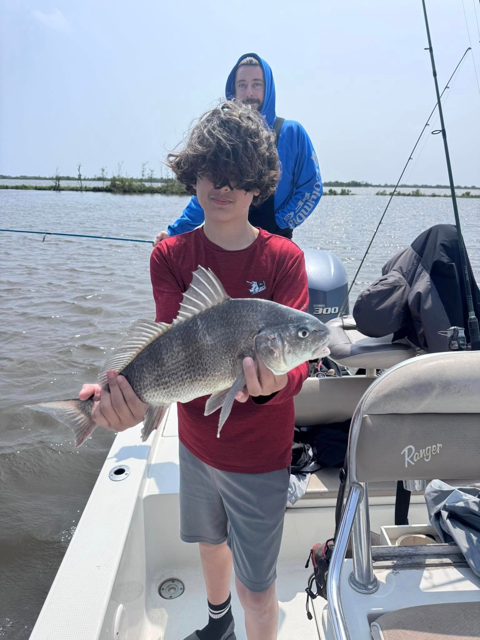 A young boy is holding a large fish on a boat.