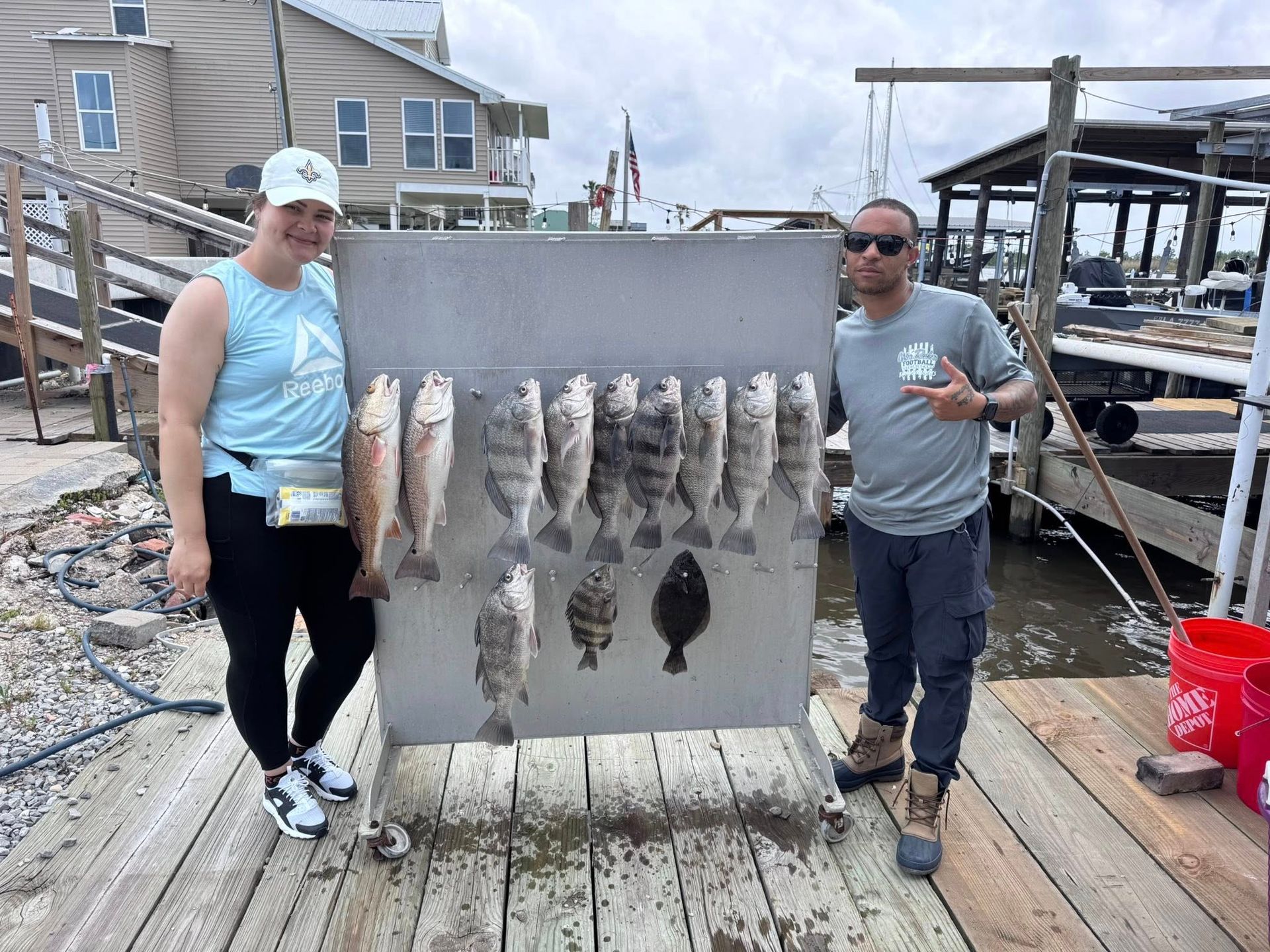A man and a woman are standing next to a display of fish on a dock.