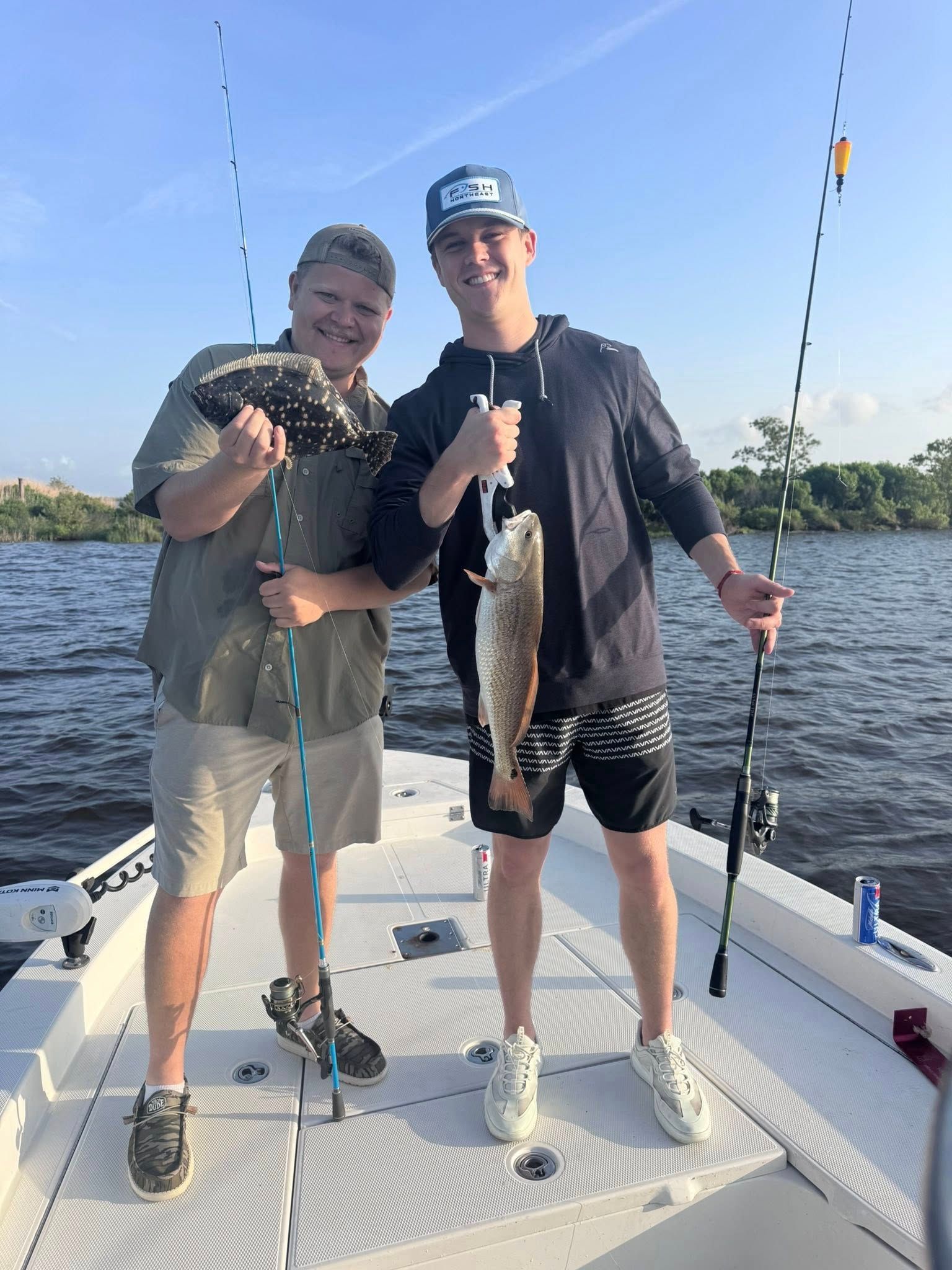 Two men are standing on a boat holding fish.