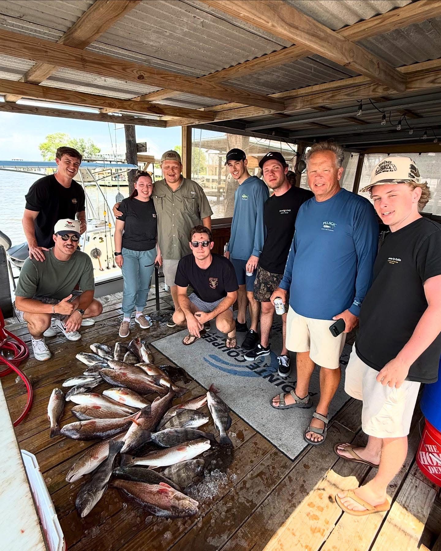 A group of people are posing for a picture with a bunch of fish.