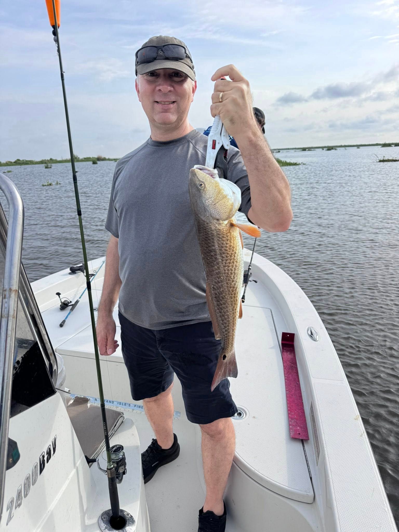 A man is standing on a boat holding a large fish.